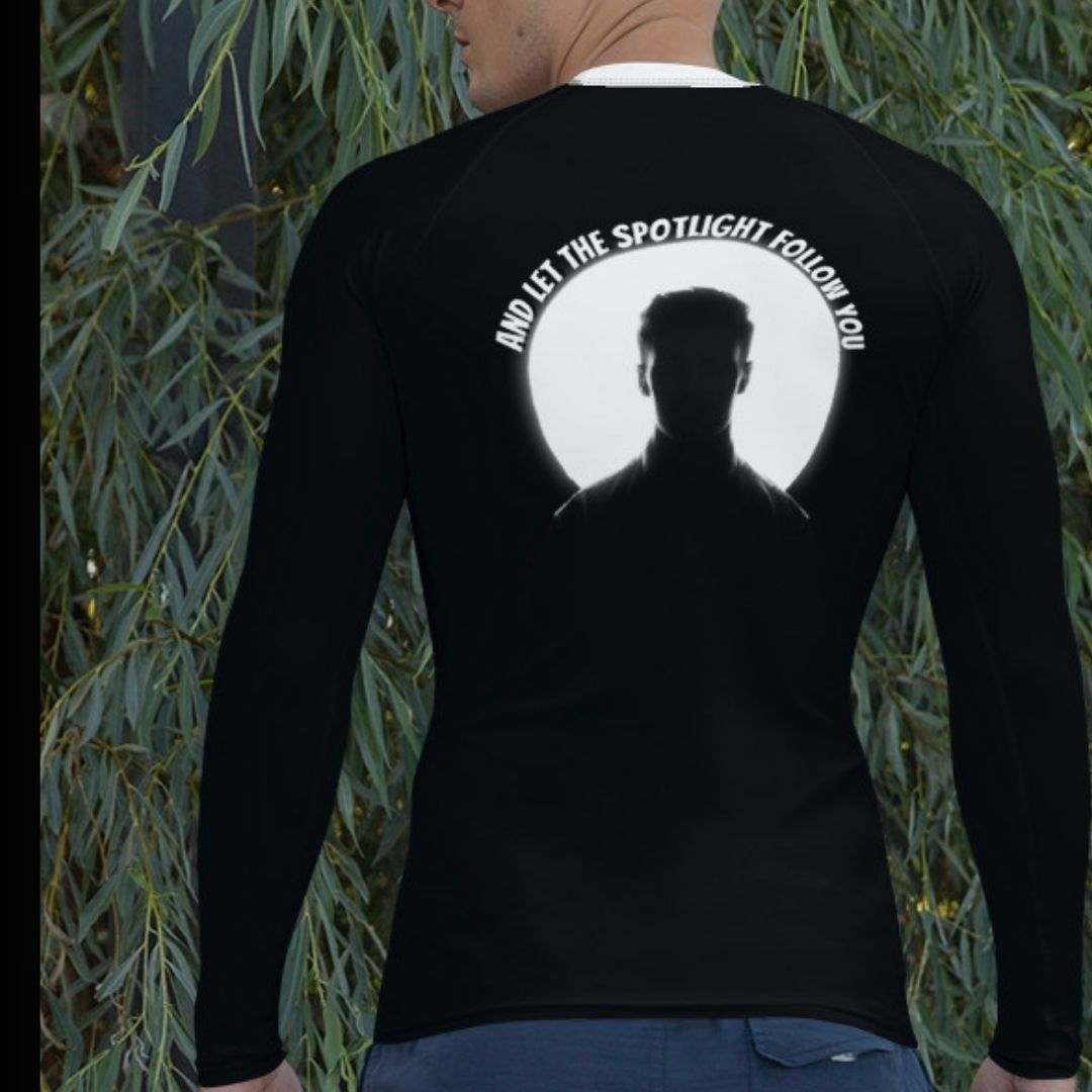 A confident man wearing the LBS Motivate Merch Men's Rash Guard, ready to lead with his best self and set goals for success